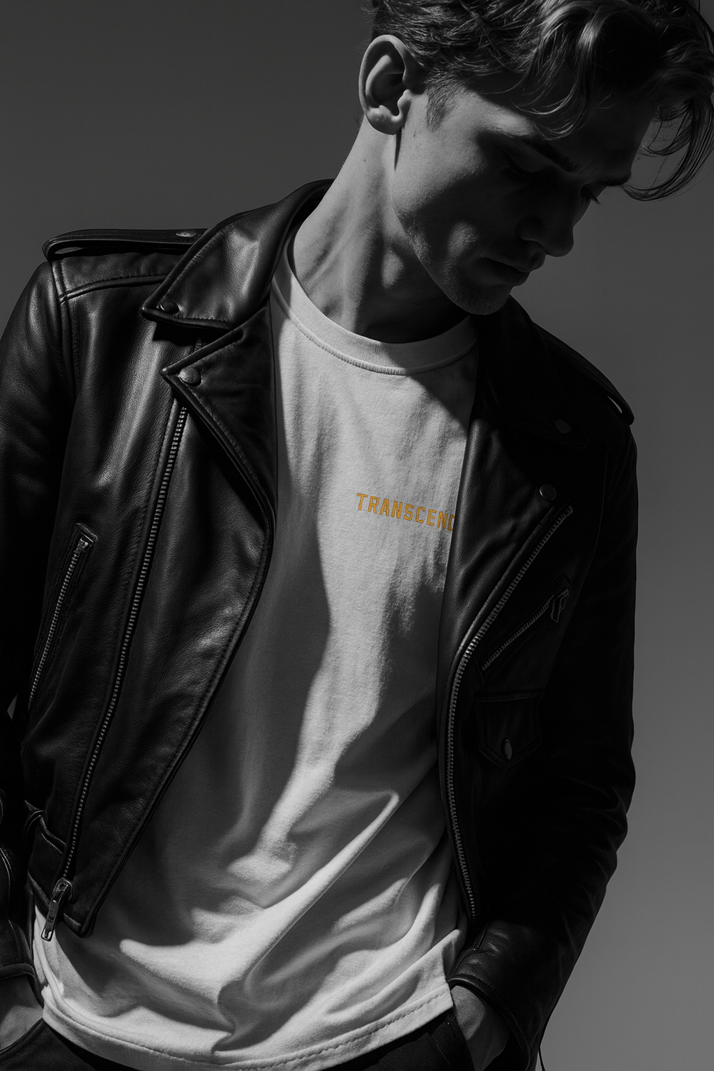Person wearing a black leather jacket and a white t-shirt with text, standing against a dark background.